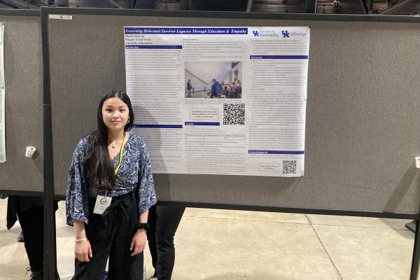 a photograph of Maylee Skovron in front of their research poster