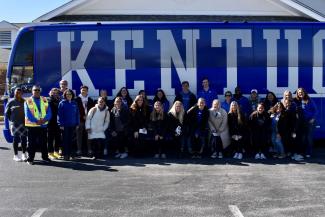 a photograph of a group of College of Public Health students in front of a University of Kentucky bus