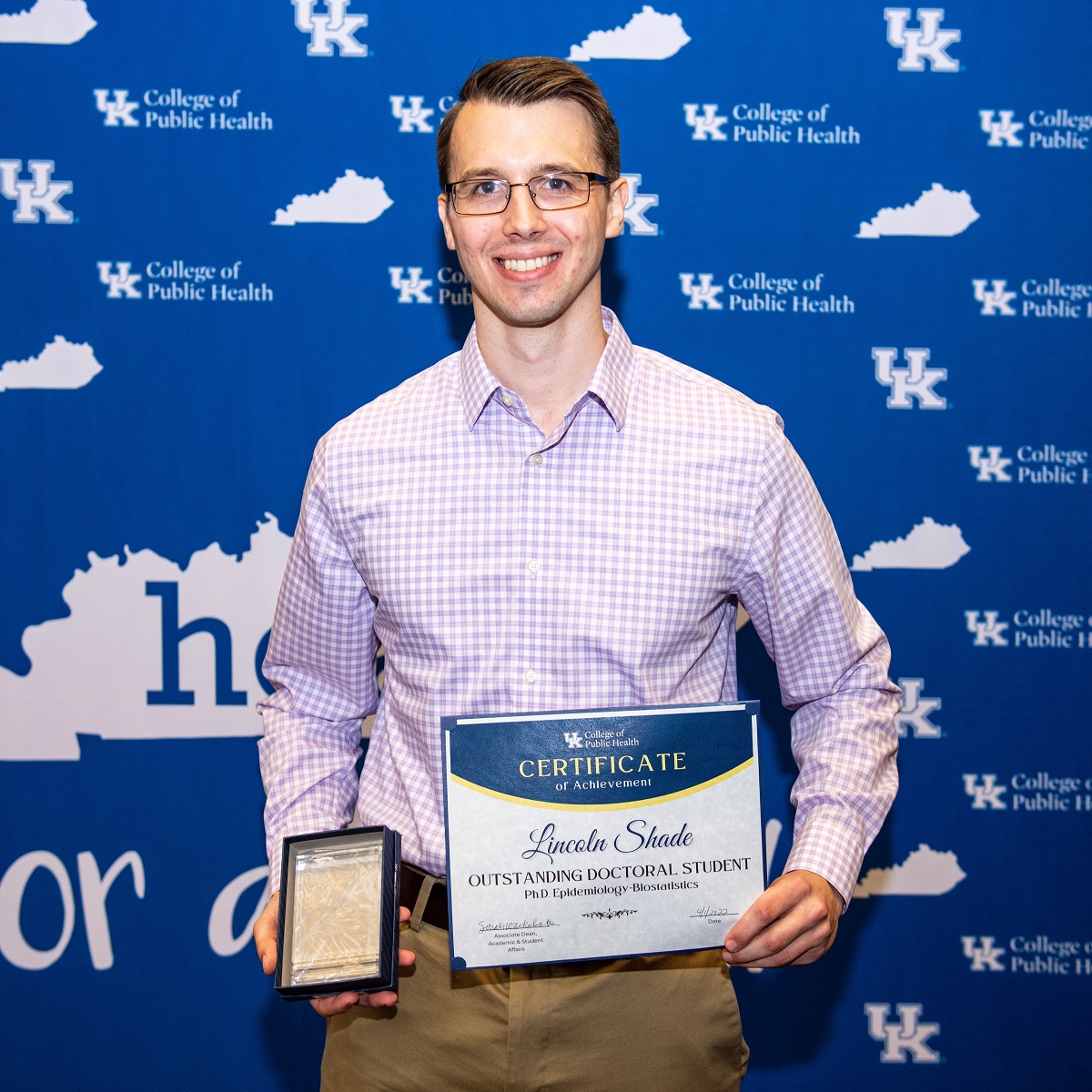 a photograph of Lincoln Shade posing with a certifcate stating "outstanding doctoral student"