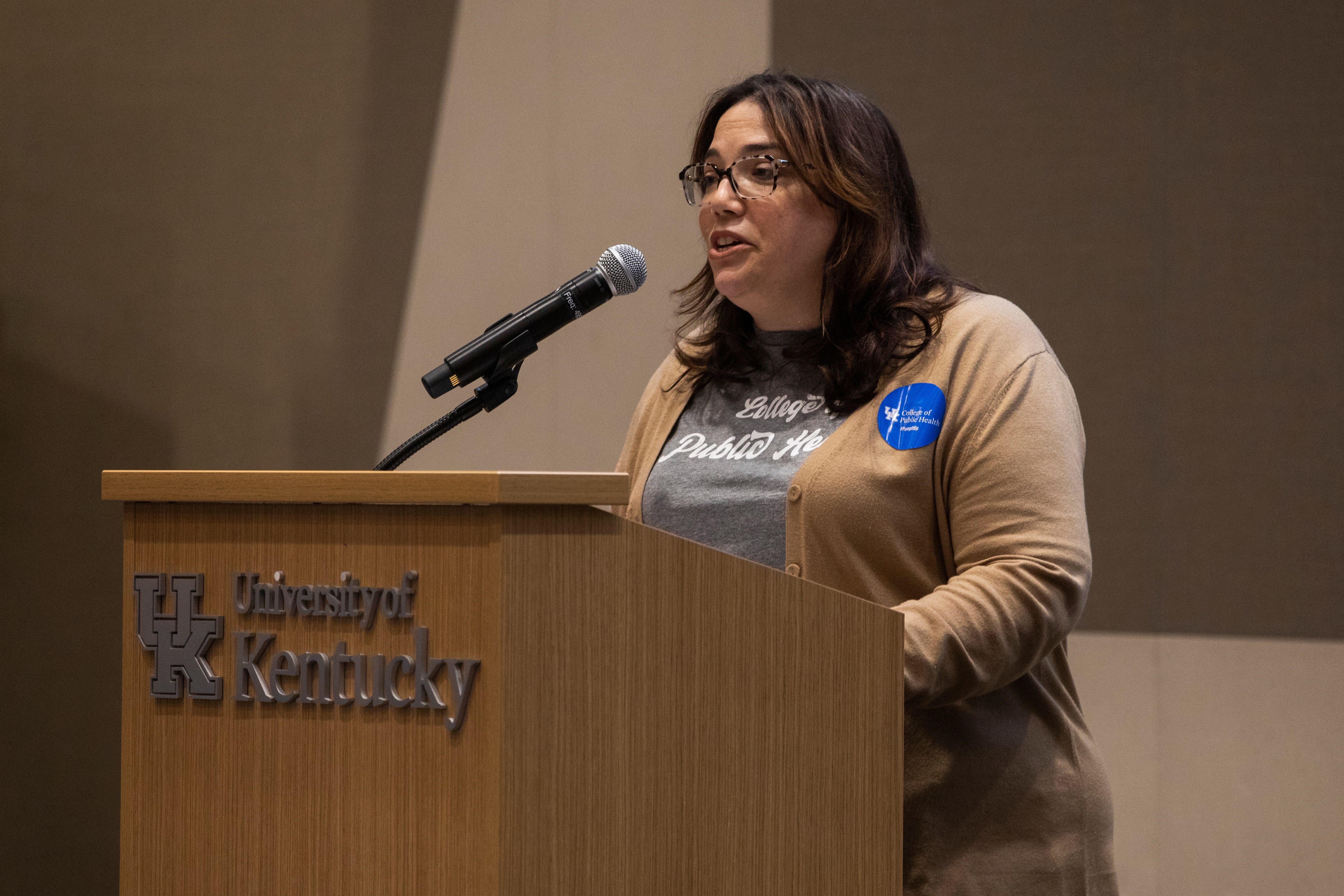 a photograph of Dr. Heather Bush speaking at a podium at the Pump It Up event