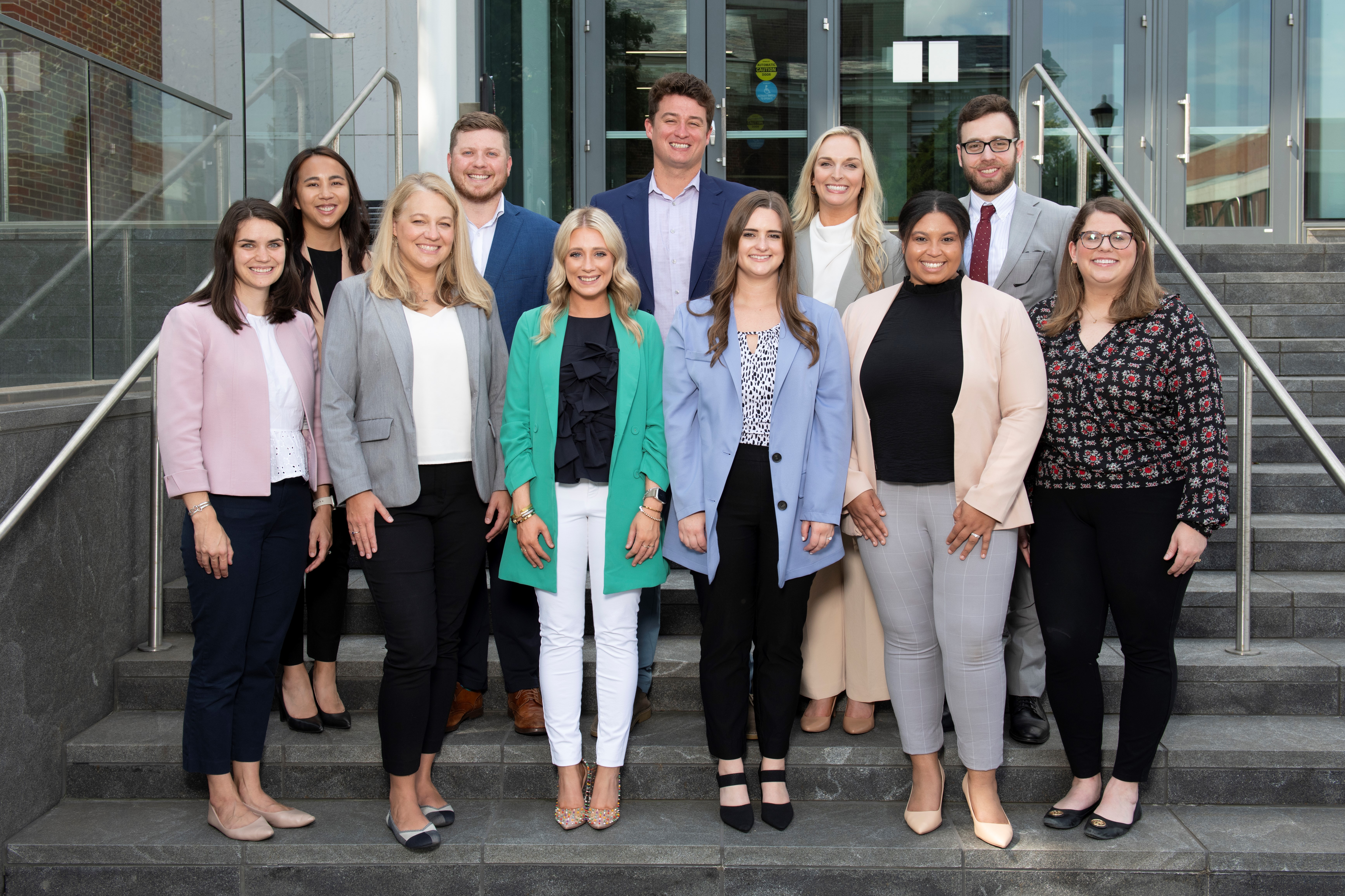 a photograph of the MHA 22-23 Alumni Leaders Council standing on steps. Top – Angel Ho, Larrin Collins, Lucas Brooks, Maggie Owens, Majd Jabbour Bottom - Casey Brackett, Kristin Green, Boone, Natalie Cooper,  Kayla Kraske, Kaylee Gaspard-Summers Not Pictured: Brianna Butler. Joanne Imbert, Reynalda Davis, Kayla Wilfong, Logan Bryer, Rhithvi Melanta, Blake Freeman, Jennifer Tabares, Cara Mets