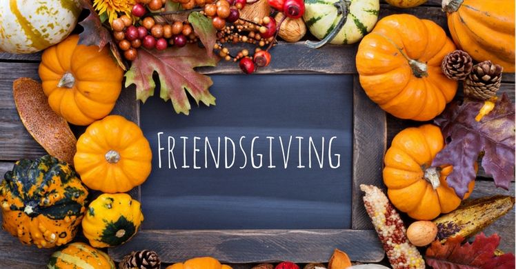 picture of a wooden sign stating "Friendsgiving" surrounded by pumpkins and other Fall-like objects