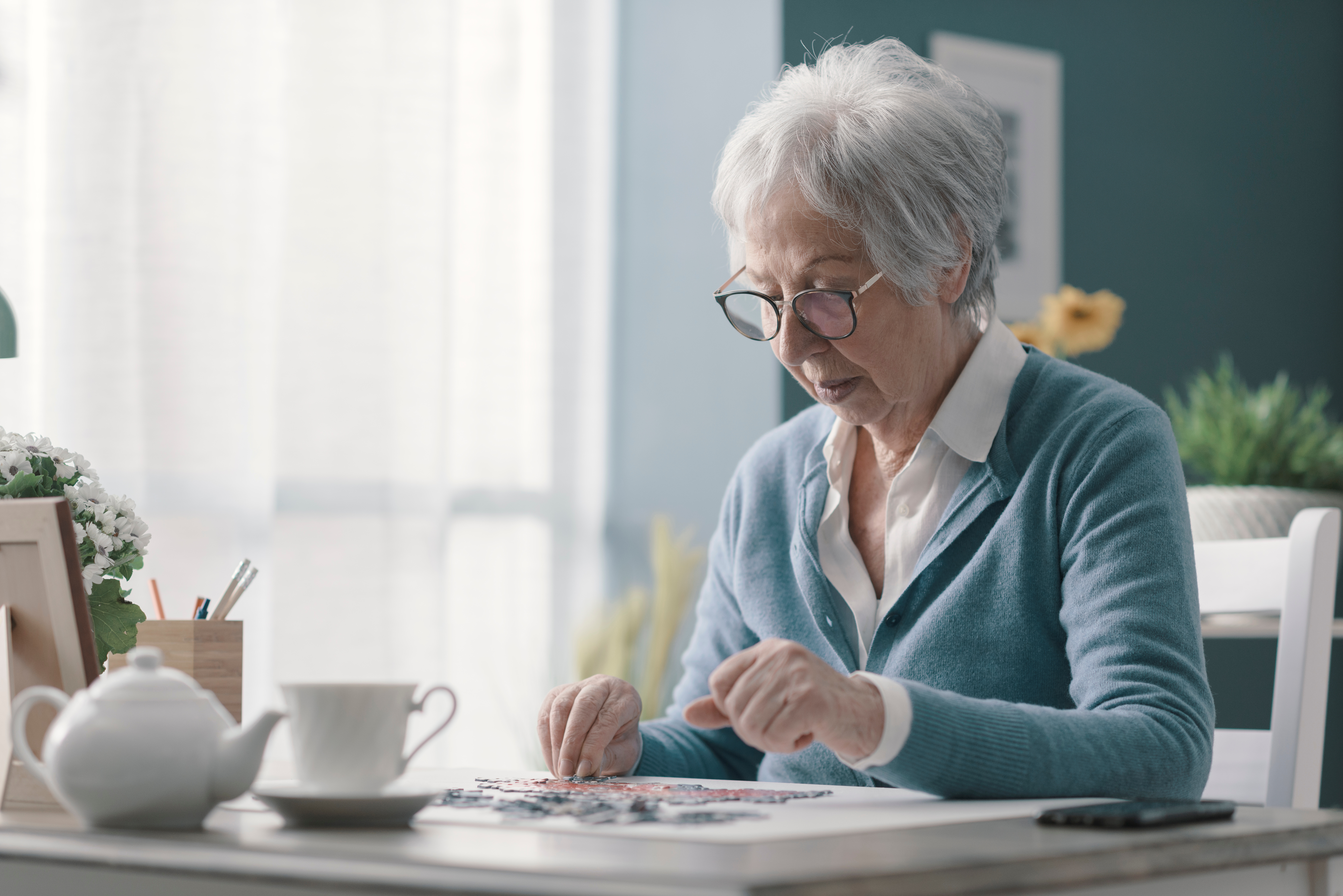 a photograph of a senior woman sitting at desk and solving a puzzle