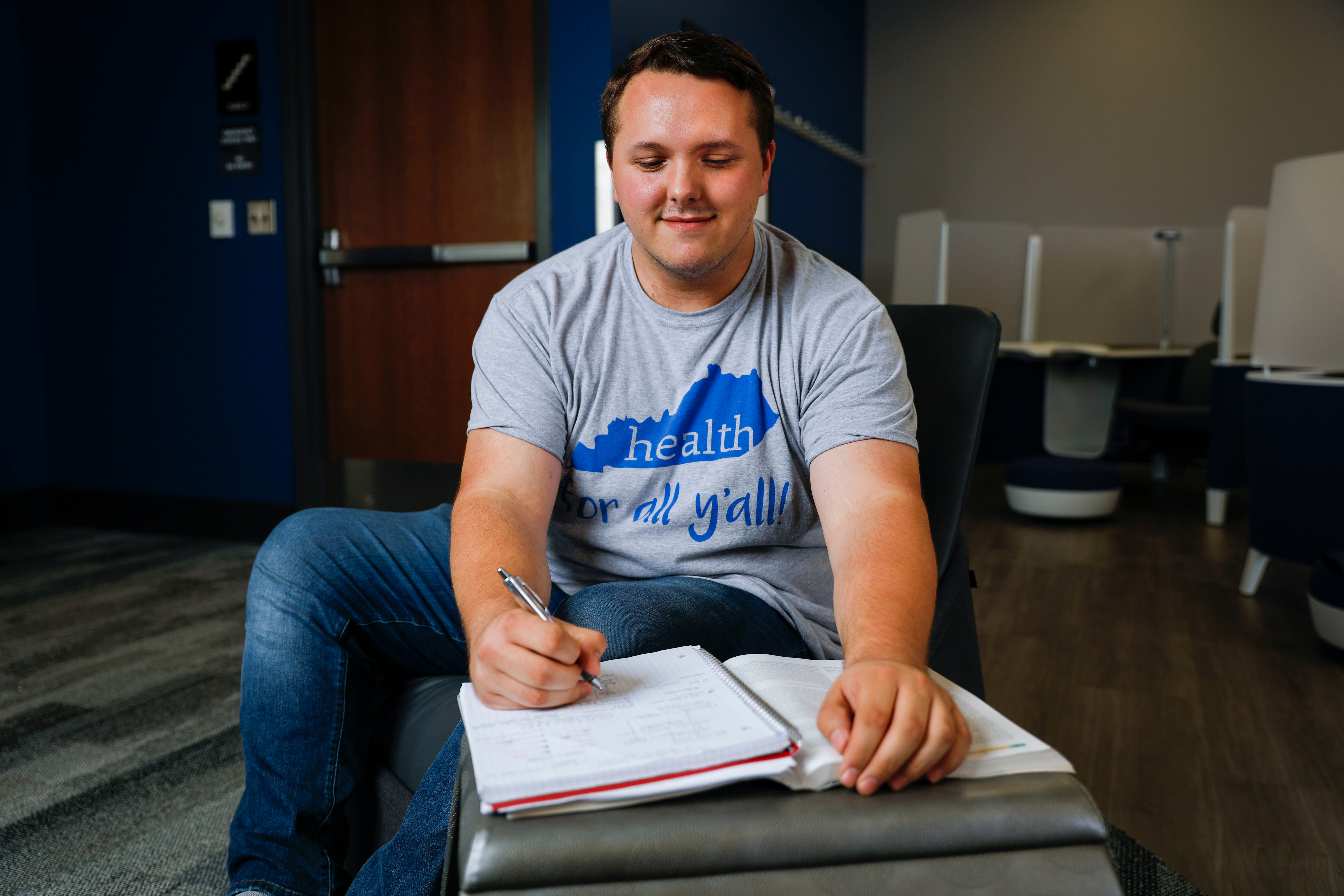 a photograph of Dakota Halbert studying while writing in a notebook