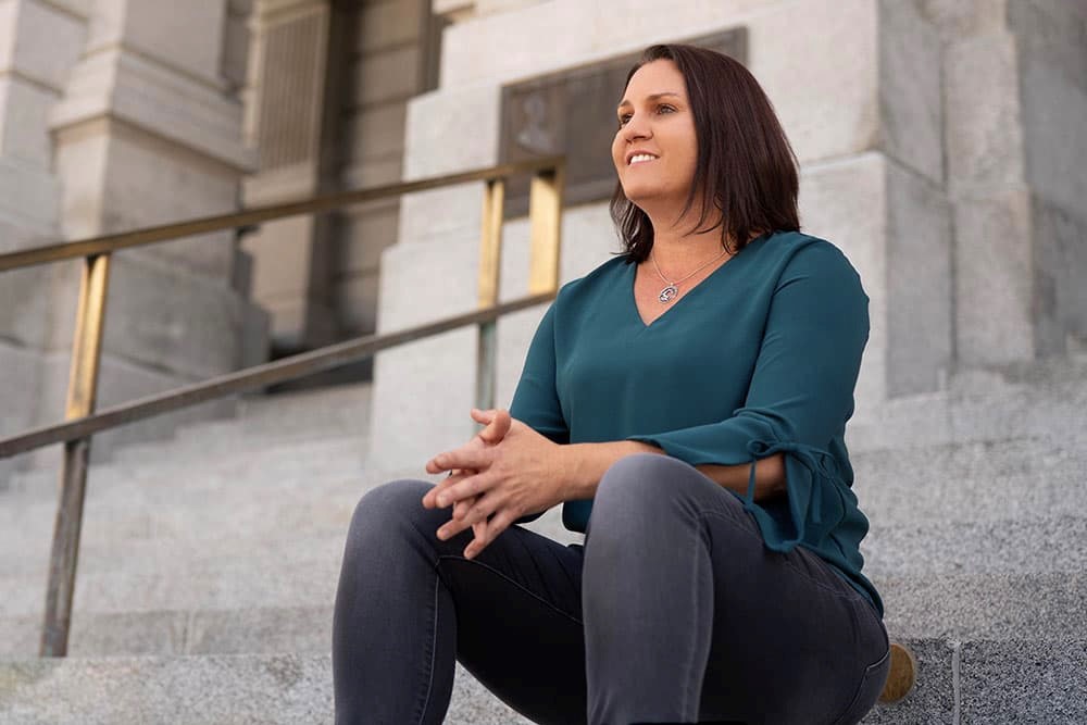 Picture of Danielle Varda, PhD, sitting down on stairs and smiling