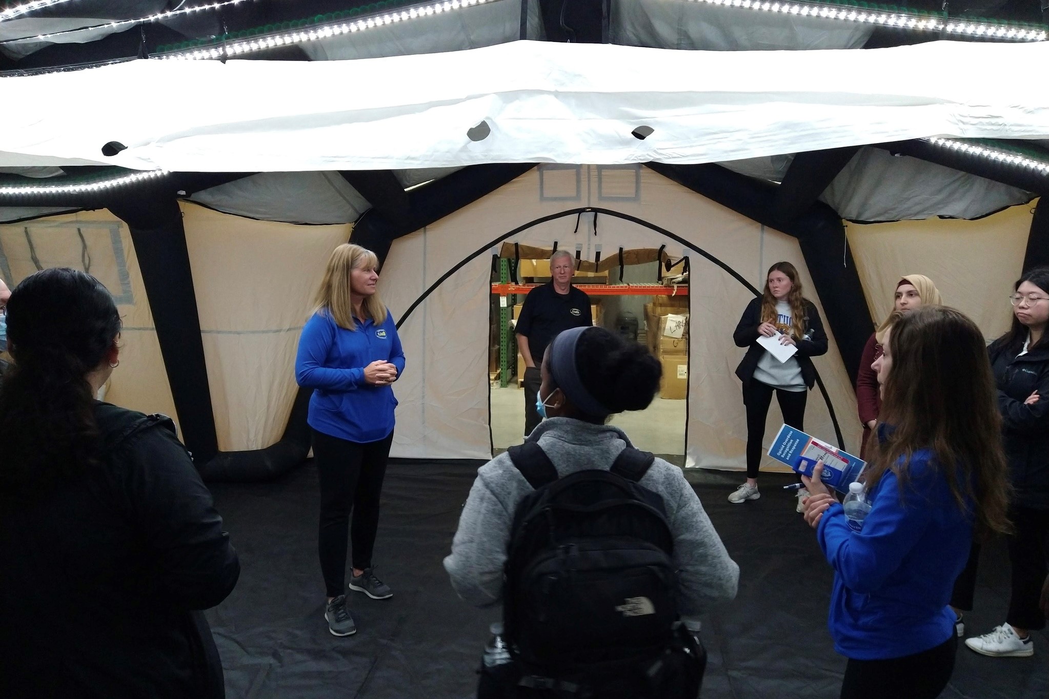 Angela Kik speaking and showing the mobile hospital ten within the emergency preparedness warehouse