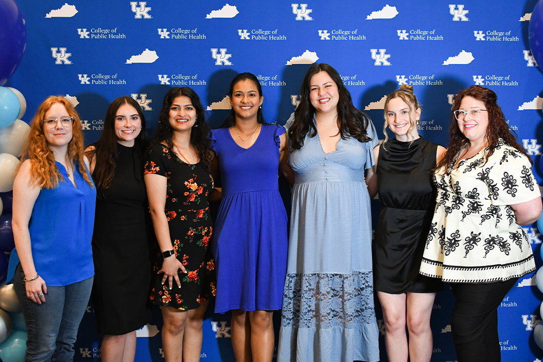 a photograph of college of public health students at an event posing for the camera in front of a backdrop
