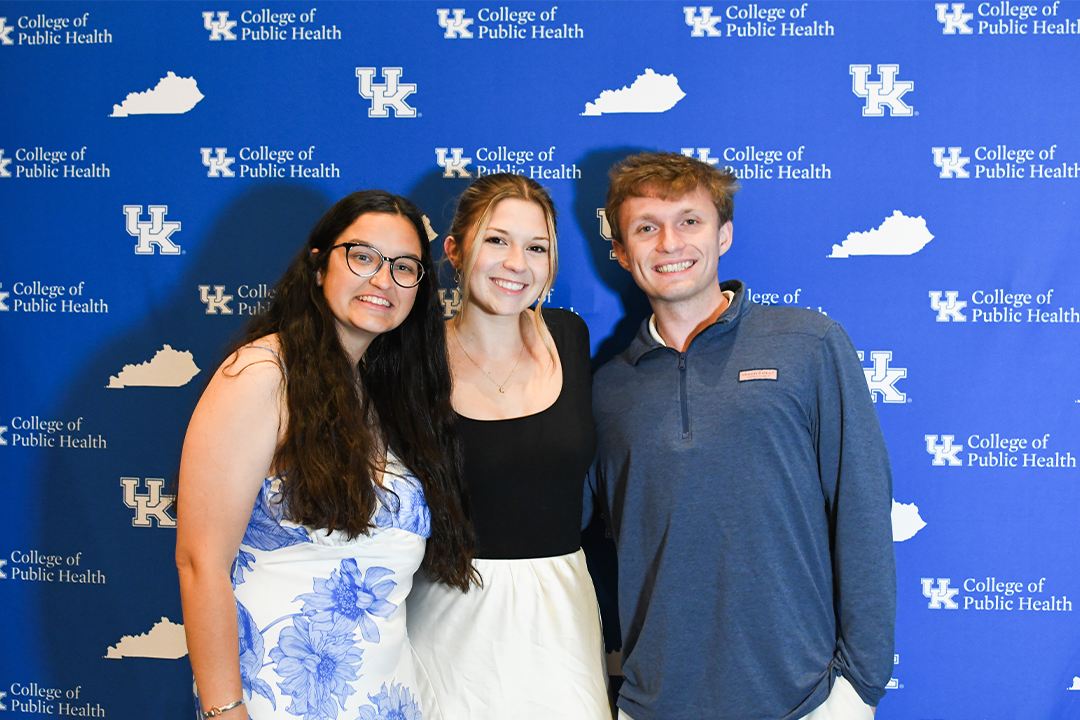 a photograph of three college of public health students posing for the camera in front of a backdrop