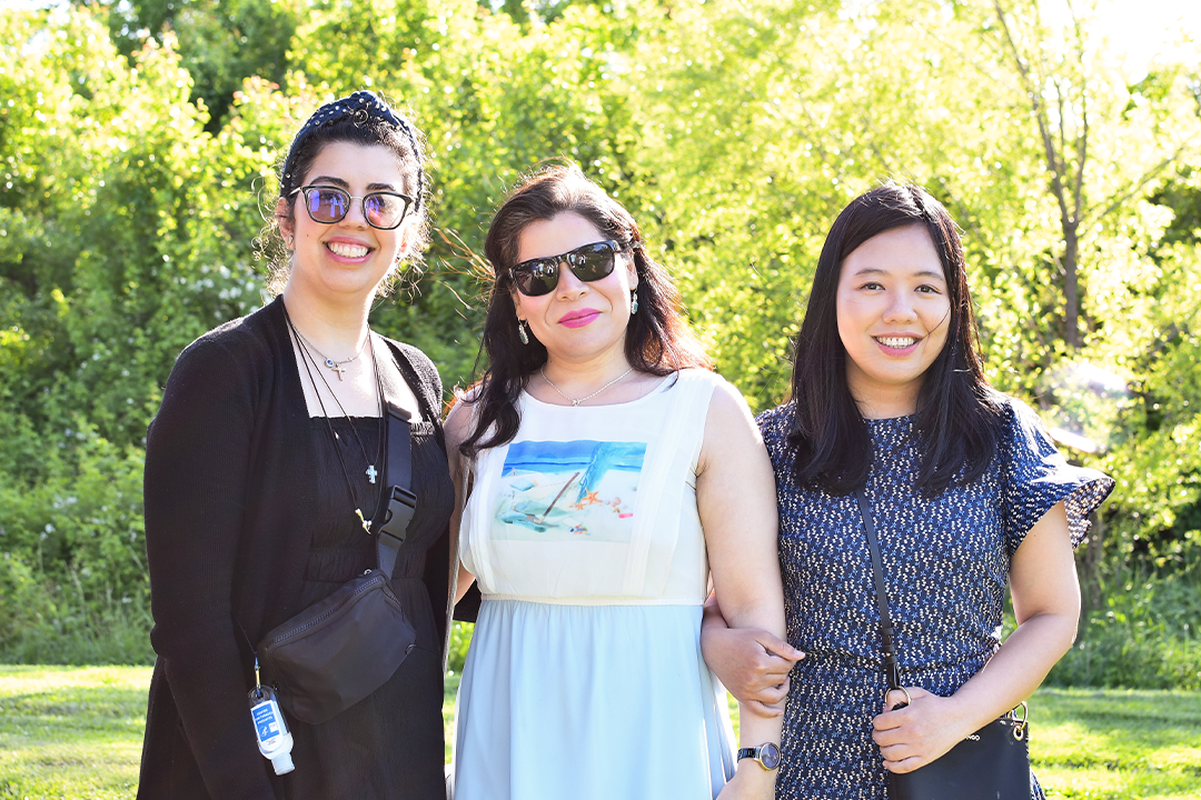 a photograph of three CPH students posing for the camera at an event in a park