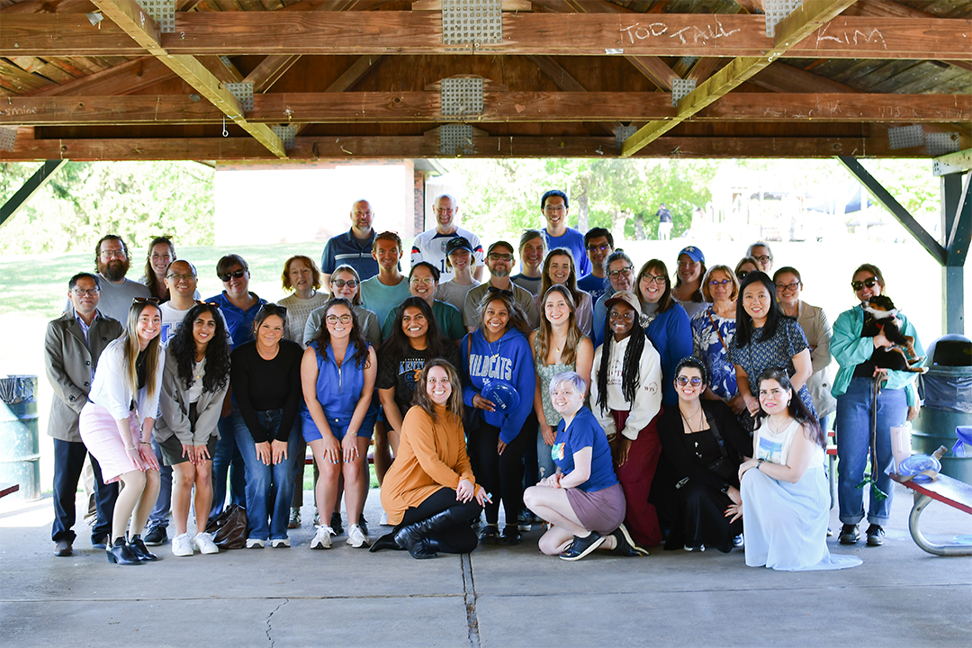a group photograph of CPH faculty, staff, and students in a park pavilion at an event