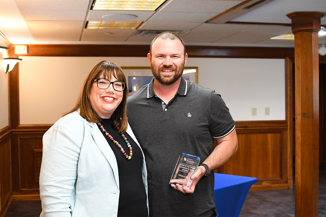 a photograph of Todd Burus posing with their award next to Heather Bush