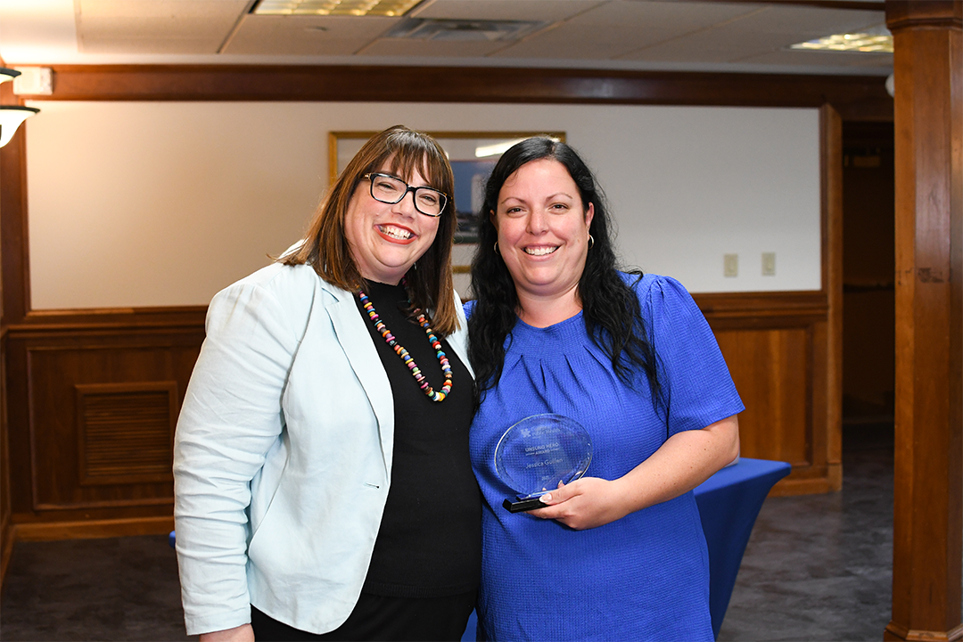 a photograph of Jessica Guillen posing with their award next to Heather Bush