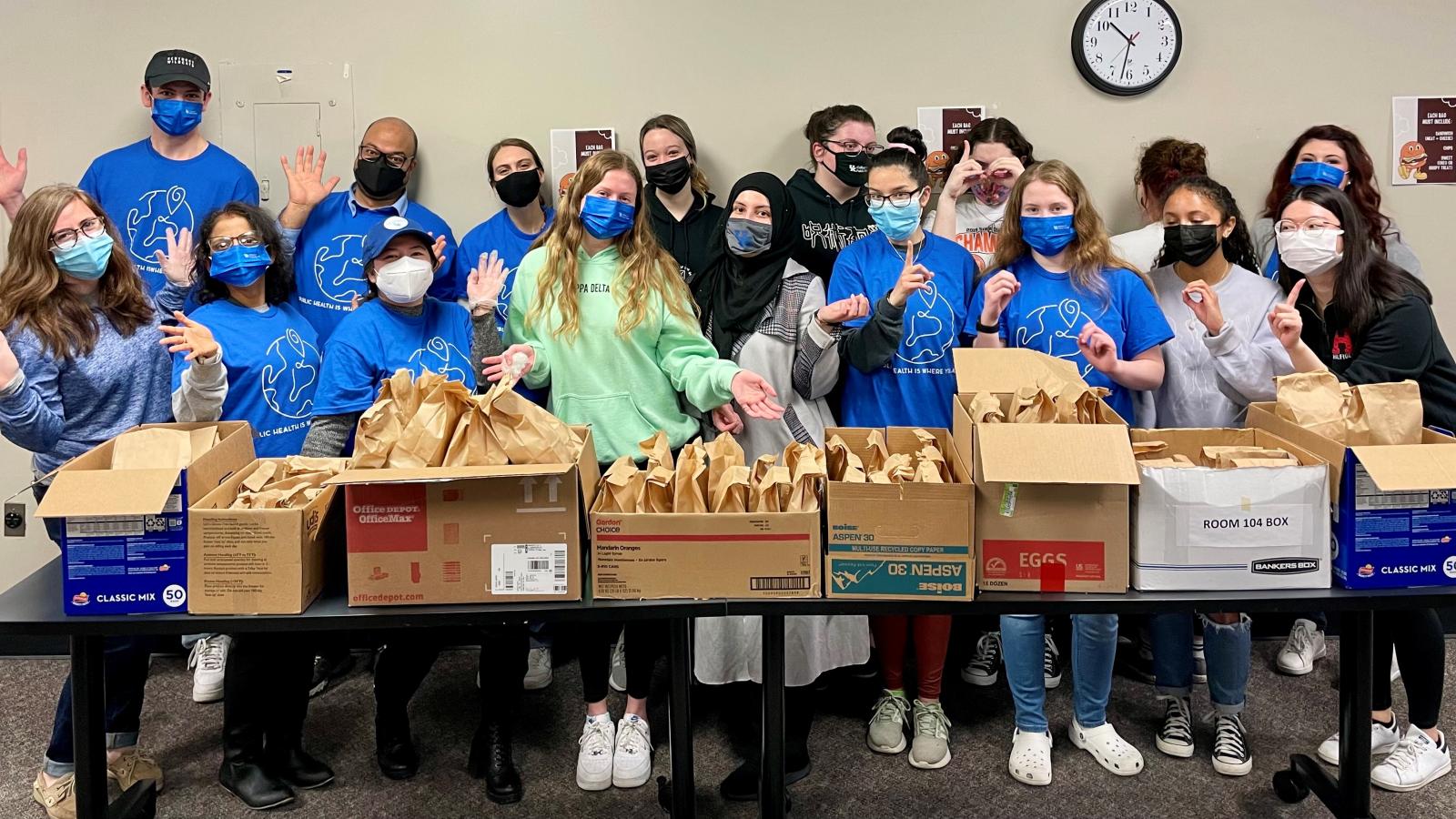 a photograph of College of Public health students behind a table of food