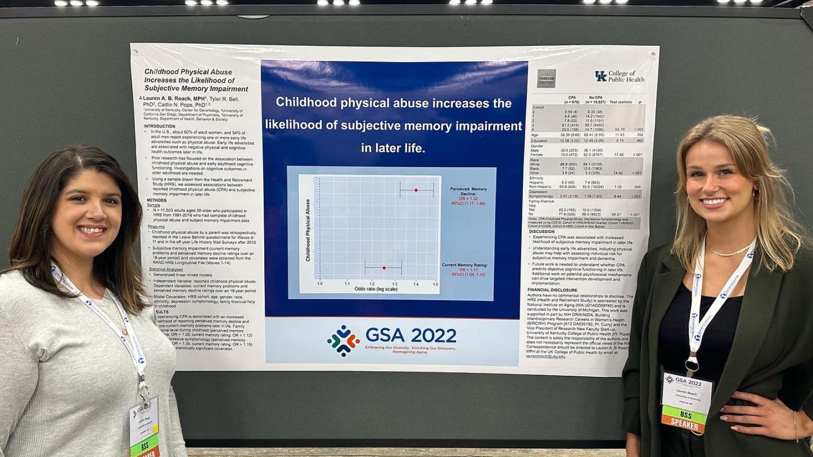 picture of Caitlin Pope and Lauren Roach standing in front of a research poster