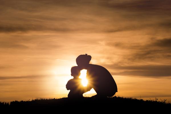 a photograph of a mother and child silhouetted in front of a sunset