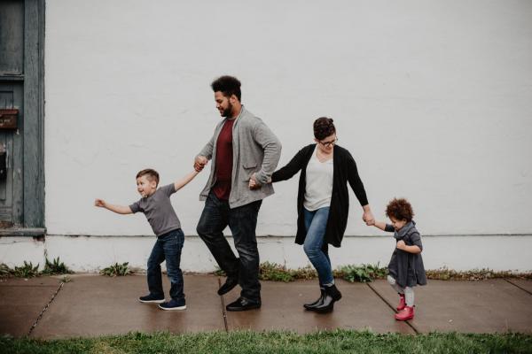 a photograph of a family walking hand-in-hand along a sidewalk