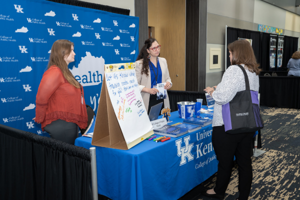Pictured is Janie Cambron behind a booth speaking to an attendee at the 2022 KPHA Spring Conference