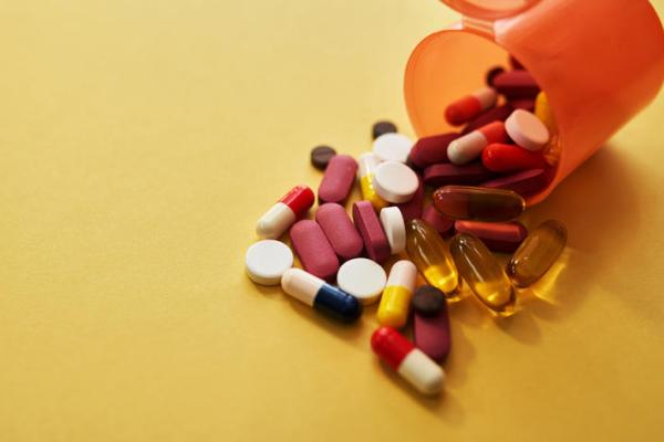 a stock photograph of a medication pills bottle knocked over with different types of pills spilling out