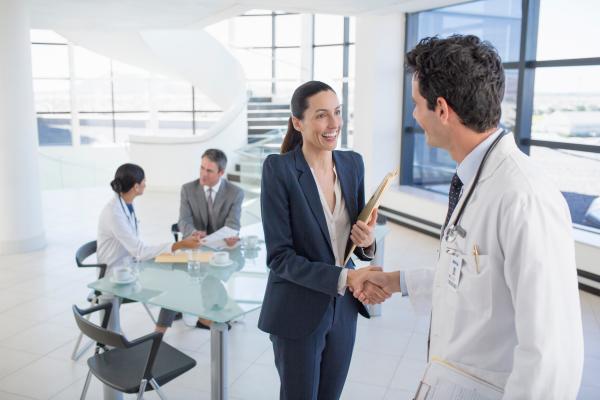 Businesswoman and doctor handshaking in meeting