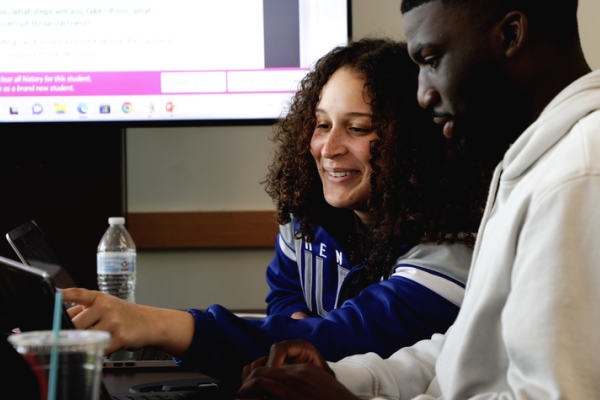a photograph of Ahsley Wright working with a student on a laptop computer