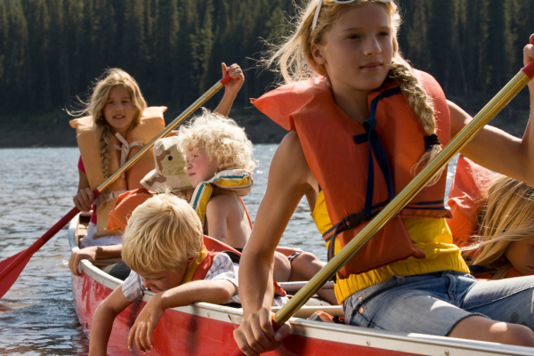 a photograph of children paddling a canoe