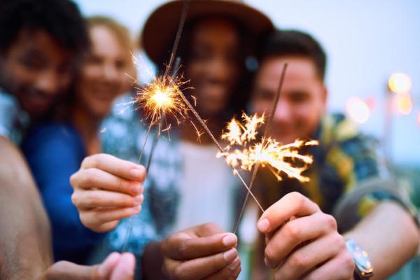 a photograph of people holding up sparklers to the camera