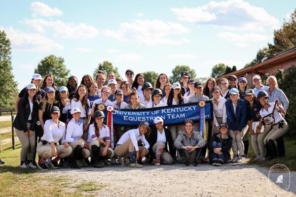 a photograph of the entire University of Kentucky Equestrian Team posing with their banner and medals