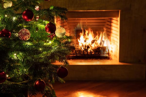 a photograph of a lit fireplace with a Christmas tree next to it