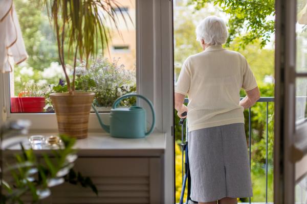 a photograph of an elderly woman looking out at their garden