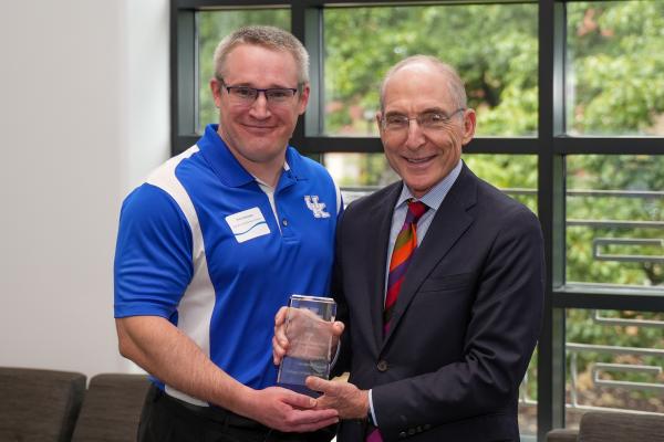 a photograph of Phillip Westgate posing with their award alongside Eli Capilouto