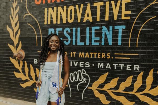 a photograph of Alexandria Thomas posing with their graduation stole and cord