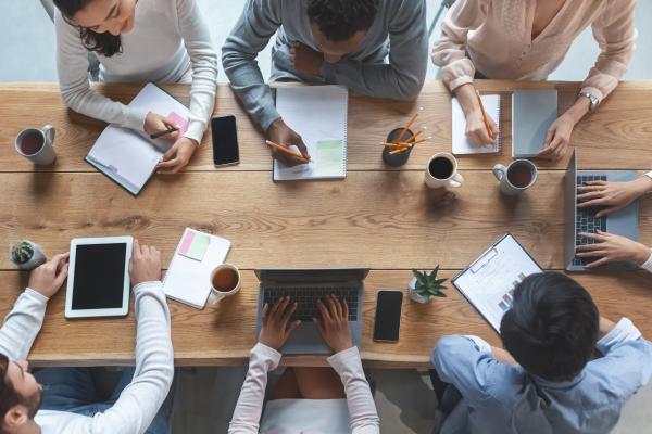 a photograph of a birds-eye view of a conference table where people are having an office meeting