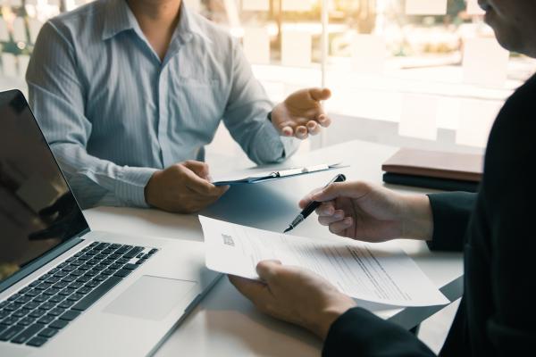 a photograph of two businesspeople talking with paper sheets in their hands