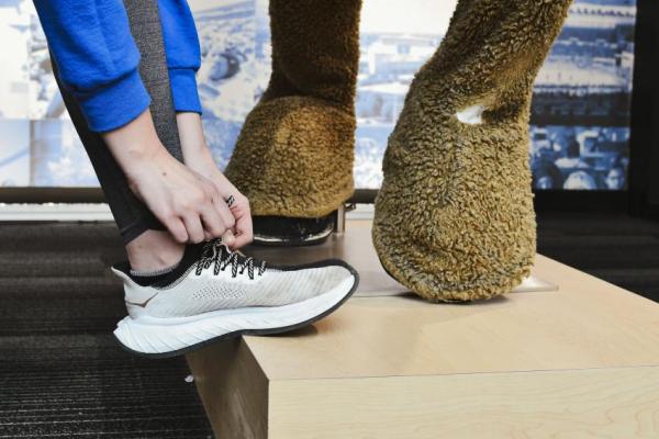 a photograph of someone tying their sneakers next to a horse statue