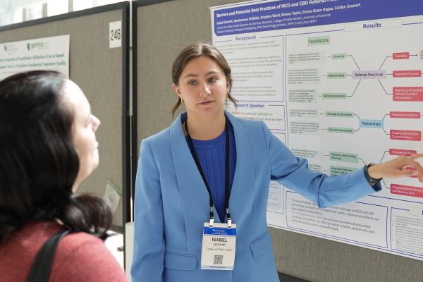 a photograph of Isabel Schmitt talking about their poster at the conference