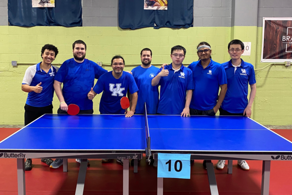 a photograph of Xizhi Xu and the other table tennis players posing behind a ping pong table