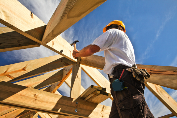a photograph of a construction worker hammering into a building frame