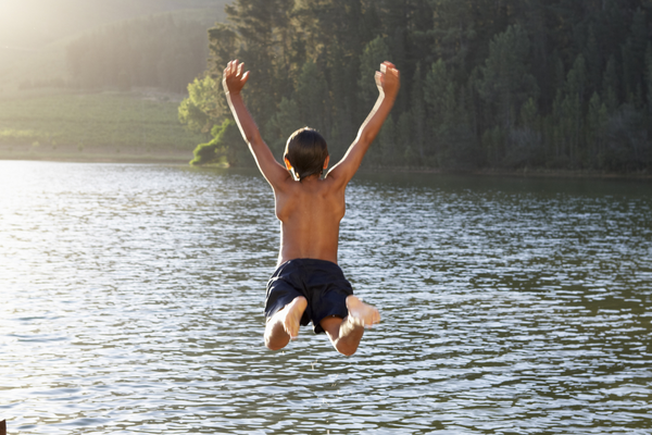 a photograph of a little boy jumping into a lake