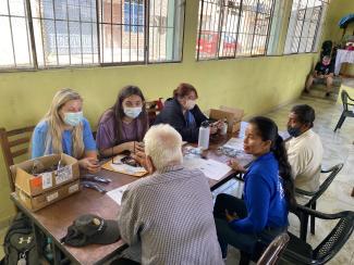 students sit a table with Ecuadorian people