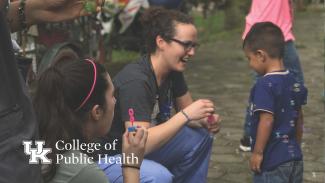 a photograph of a student blowing bubbles with a child, and the College of Public Health lockup is in the left corner