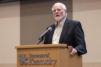 a photograph of Dr. James Holsinger speaking at a podium at the Pump it Up Event