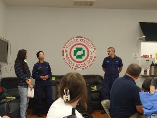 a photograph of two members of the Floyd County Kentucky Emergency & Rescue Squad Inc. speaking to a small group of people in their builkding