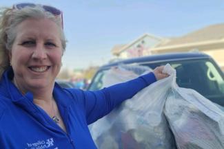 a photograph of Dr. Maureen Jones holding up bags of trash