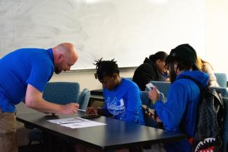 a photograph of Benji Bryant helping students with their music bingo cards