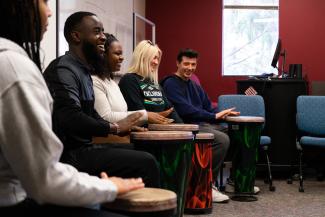 a photograph of students playing bongos in a classroom