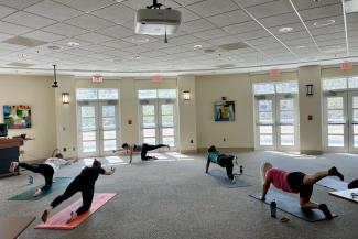 a photograph of people in an exercise room on yoga mats doing a pose
