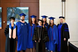 Public health students pictured in graduation regalia with faculty Maureen Jones, Julia Costich and Martha Riddell