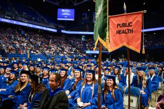 Public health graduates smiling while seated at ceremony