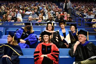 Faculty members Anna Hoover, Angela Carman, Martha Riddell (back row) and Kathleen Winter, Emily Slade, Steve Browning (front row) in regalia watching ceremony