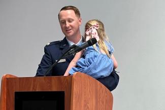 Major Marcus Hincks at a podium holding his daughter